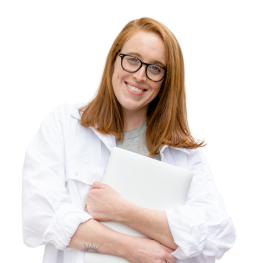 Smiling public relations professional with red hair wearing a white shirt and holding a laptop
